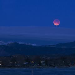 Blood moon rising over mountains.