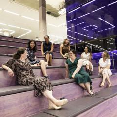 A group of seven women entrepreneurs from UQ sit on a staircase at the St Lucia campus.