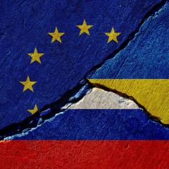 cracked concrete wall with painted eu, russia and ukraine flags