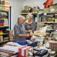 An image of UQ Alumni Book Fair rare book co-convenors Jan Thompson and Anne Mullins surrounded by books.