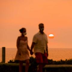 A man and woman are seen along a foreshore as the sun sets with smoke haze.