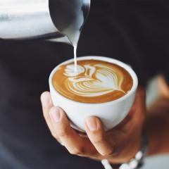 A barista pours milk into a coffee cup.