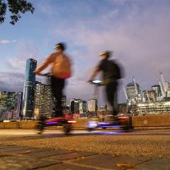 People ride scooters in the evening along Southbank in Brisbane