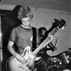 A black and white image of a guitarist and drummer.