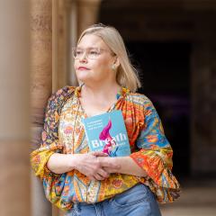 An image of Carly-Jay Metcalfe standing in UQ's Great Court with her new book, Breath.