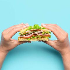 An image of hands holding a ham and salad sandwich.