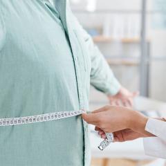 Close-up of doctor measuring waist of overweight man.