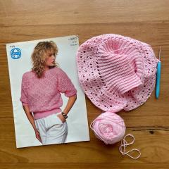 A pattern for a knitted sweater next to a ball of yarn and a knitted pink circle