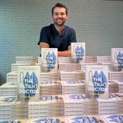 An image of UQ alum and cancer survivor Dr Ben Bravery with copies of his new book 'The Patient Doctor'.