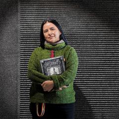 An image of Dr Sol Rojas-Lizana, who grew up in Chile during the military dictatorship of former president Augusto Pinochet. She is holding the graphic novel she co-authored, called 'Historias Clandestinas'.