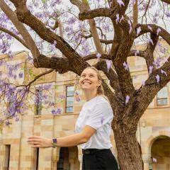 An image of a woman throwing jacaranda flowers in UQ's Great Court