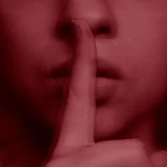 An image of a woman holding a finger over her mouth indicating to be quiet.