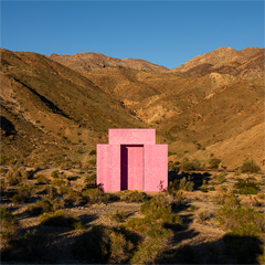 Image of a small pink concrete structure in the middle of a desert enironment