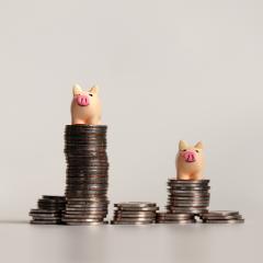 Stacks of coins with small toy pigs on top.