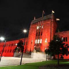 Forgan Smith Building at UQ St Lucia lit by red lights at night.