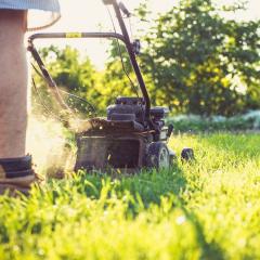 Young man mowing the grass in work boots.