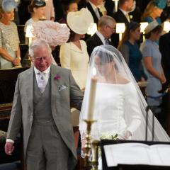   Image: Jonathan Brady - WPA Pool/Getty Images - image of Prince Charles in a grey suit walking Meghan Markel down the aisle, she wears a white wedding gown 