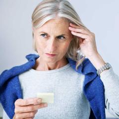 Woman with one hand on her head looking at a post-it.