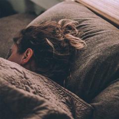 Woman sleeping on bed under blankets.