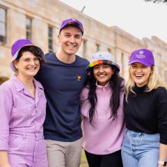 An image of 4 UQ students (3 women and one man) standing in UQ's Great Court wearing new UQ Pride merchandise, which goes on sale on 1 June 2023.