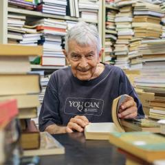 UQ Alumni Book Fair volunteer and former Dean of the Faculty of Arts Don Barrett AM surrounded by thousands of books.