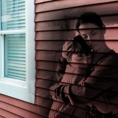 Portrait of mother hugging small daughter indoors at home, housing-crisis concept.