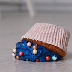 Image of a cupcake with blue icing that has been dropped on the floor