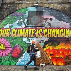 A man walks past a mural in Glasgow, which says 'Our climate is changing'.