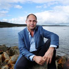 This is an image of Cameron Costello sitting on edge of the water.