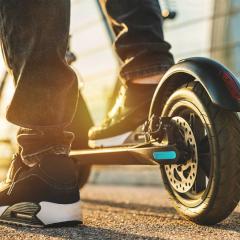Close up of young man at sunset with electric scooter or e-scooter.