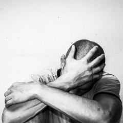 An image of a lonely man sitting with his head in his hands.