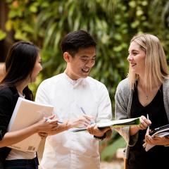 Students looking at each other and smiling, they are in an outdoor setting.