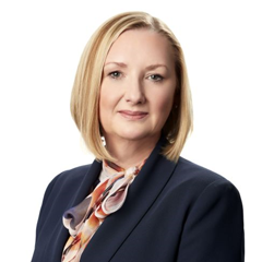 Headshot of a blonde woman in business atire looking at the camera