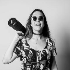 Chelsea Morrigan poses with her camera in a black and white photograph.