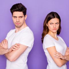 An image of an couple standing back-to-back looking annoyed.