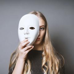 An image of a woman holding a mask partly covering her face